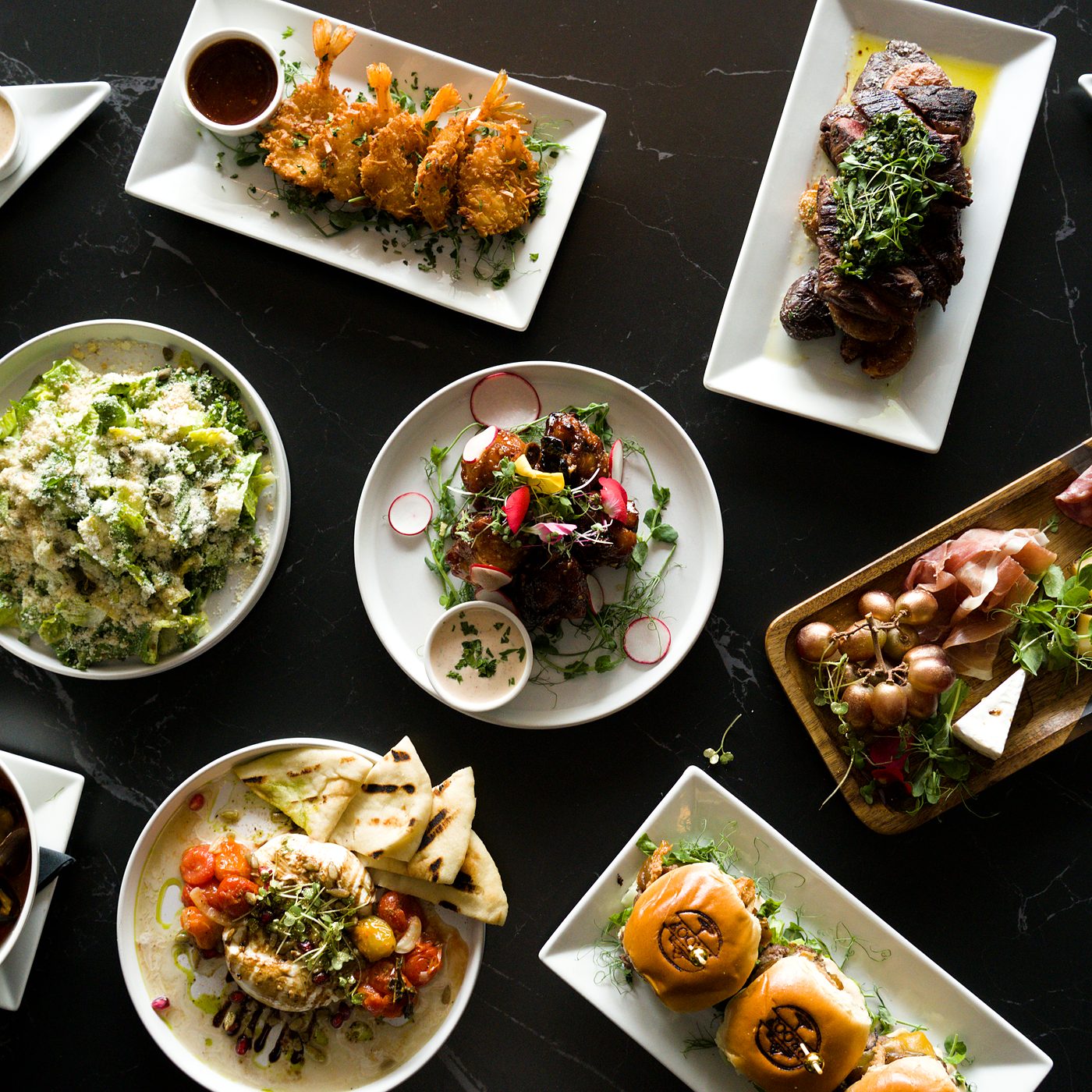 Overhead table spread of restaurant dishes on a black marble table, Fort Lauderdale food photography